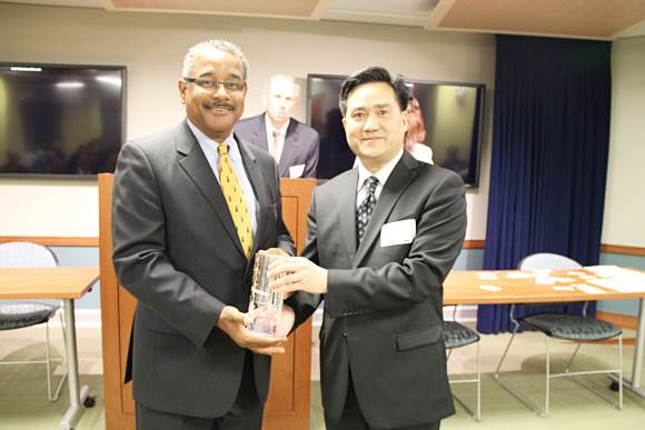 Mr. Frank Cao is presenting a gift to Mr. Antonio Doss
